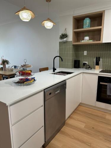a kitchen with white cabinets and a sink and a stove at Koombana Bay beach Homestay in Bunbury