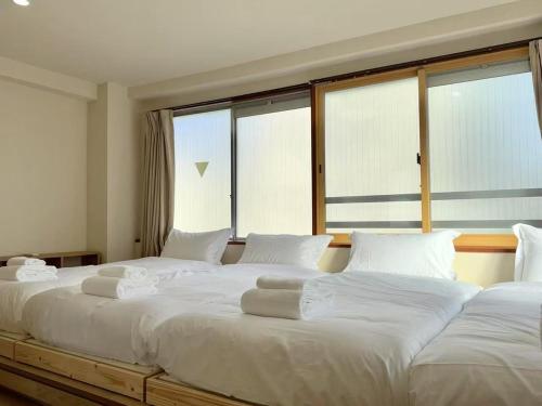 Habitación con 2 camas blancas grandes y ventanas grandes. en Ikeda Ueno 501 Quad room Room, en Tokio