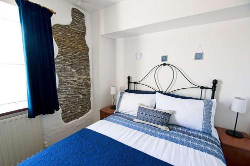 a bedroom with a bed with blue and white pillows at Old Bakery Cottage in Mortehoe