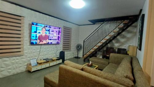 a living room with a couch and a tv at The Cozy Glass House by the Sea in Bauang