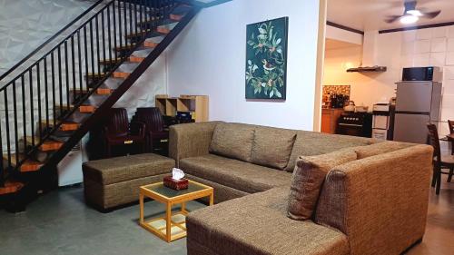 a living room with a couch and a staircase at The Cozy Glass House by the Sea in Bauang