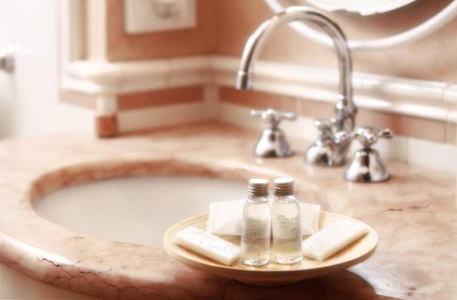 a bathroom sink with two bottles on a tray at Hotel Arnaldo Aquila D’oro in Rubiera