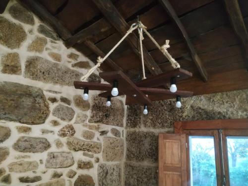 a chandelier hanging from a stone wall at Casa dos ánxeles VUT-OR-1310 in Trasmiras