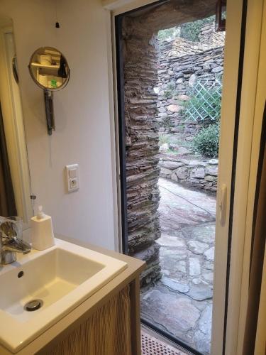 une salle de bain avec un lavabo et un mur en pierre dans l'établissement Ancienne bergerie de Torteillan, à Combes
