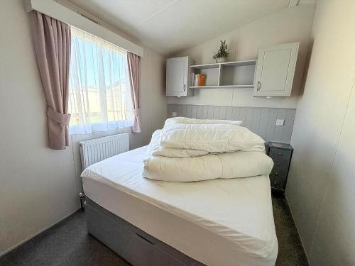 Cette petite chambre comprend un lit avec des draps blancs. dans l'établissement Beautiful Caravan At Manor Park Holiday Park In Hunstanton Ref 23060W, à Hunstanton