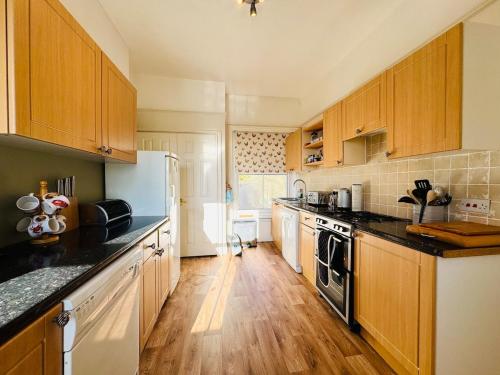 una cocina con armarios de madera y encimeras negras en NEW Seabreeze Large Family Apt Sea Views Ventnor, en Ventnor