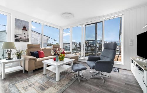 een woonkamer met een bank, stoelen en ramen bij Sutsche in Olpenitz