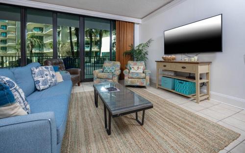 ein Wohnzimmer mit einem blauen Sofa und einem Fernseher in der Unterkunft Phoenix on the Bay 1121 condo in Orange Beach