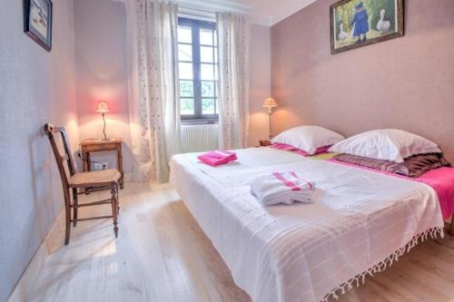 une chambre avec un grand lit blanc et une chaise dans l'établissement La Maison de Rosyne, à Aubas