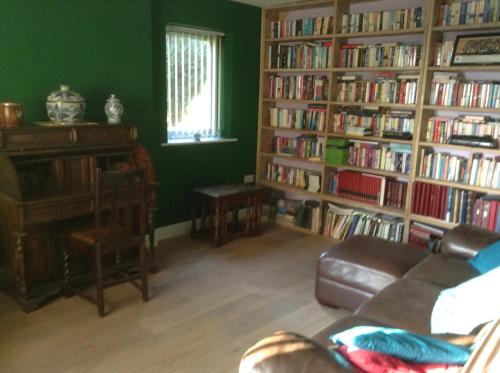 a living room with a couch and book shelves filled with books at B&B Dorwyn Manor in Avebury