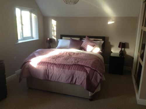 a bedroom with a bed with purple sheets and pillows at B&B Dorwyn Manor in Avebury