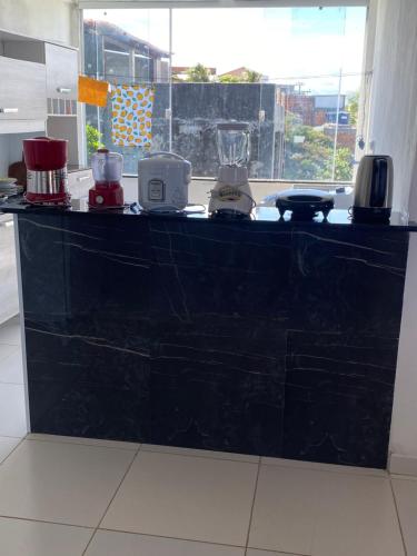 a black counter in a kitchen with appliances on it at Apto em Itaparica condomínio in Itaparica Town