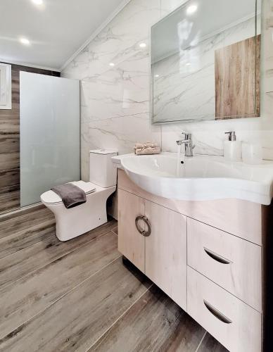 a white bathroom with a sink and a toilet at Coastal Ierapetra 1 in Ierapetra