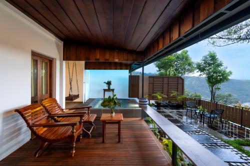 una terraza con sillas y mesas en una casa en SpiceTree Munnar, en Chinnakanal