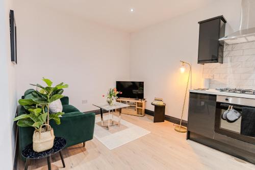 a living room with a green couch and a kitchen at Charming & Cosy 2 BR Flat, Fast Wifi -Sleeps 5 in Leeds
