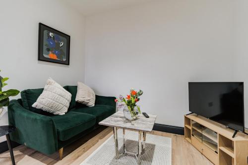 a living room with a green couch and a tv at Charming & Cosy 2 BR Flat, Fast Wifi -Sleeps 5 in Leeds