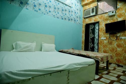 a bedroom with a bed and a tv on the wall at Shri Gauraj Dham in Chhatikara