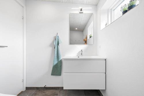a white bathroom with a sink and a mirror at Newly renovated house in the center in Thyborøn