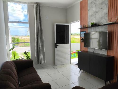 a living room with a couch and a flat screen tv at Paraíso em Aquiraz - Paz, Sol e Mar ao seu Alcance in Aquiraz
