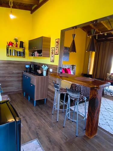 a kitchen with a bar with chairs and a yellow wall at Horizonte azul sussuarana in Gonçalves