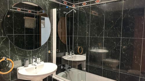 a black tiled bathroom with two sinks and a mirror at Desert Springs award-winning Golf Resort apartment in La Hoya del Camaino