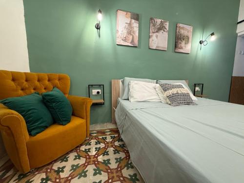 a bedroom with a bed and an orange chair at Entire Apartment in Cospicua with a Cellar! in Cospicua