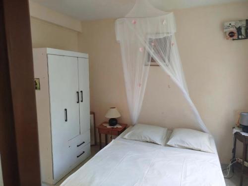 a bedroom with a white bed with a white canopy at Maison entière - La Florière Verdoyante in Le Morne Rouge