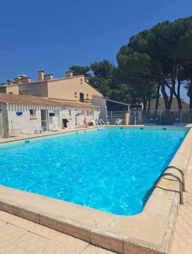 une grande piscine bleue devant un immeuble dans l'établissement 001 Ipanema le capi'nède, au Cap d'Agde