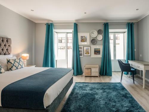 a bedroom with a bed and a desk and blue curtains at Vila Garden Guesthouse in Lisbon