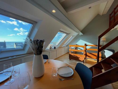 a dining room with a table with glasses and a vase at Appartement Ô Nid Perché Vue mer in Agon Coutainville
