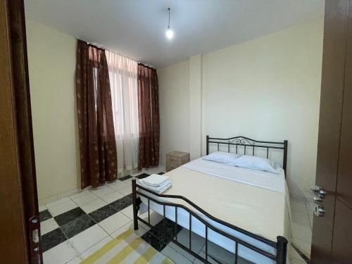 a bedroom with a bed and a large window at Bajovah Apartments & Restaurant in Tirana