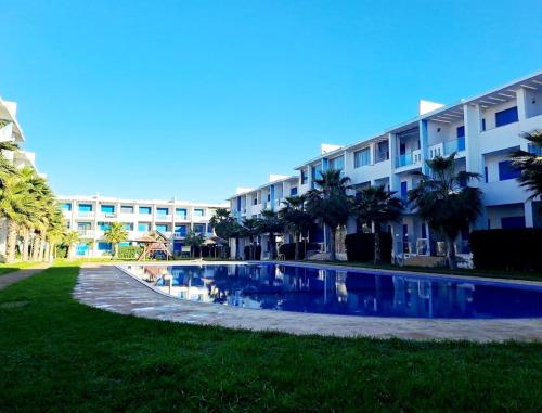 a swimming pool in front of a building at appartement à Mansouria avec piscine et accès a la mer Perla Andaloussia El Mansouria in Mansouria