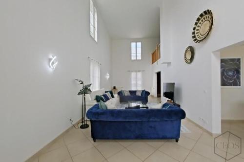 un salon avec un canapé bleu et un réveil dans l'établissement Spacieuse family house pour 14 - Disneyland Paris, à Magny-le-Hongre