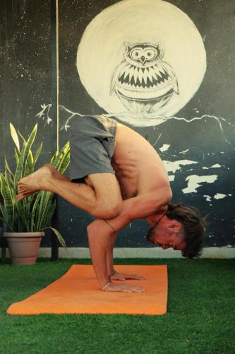 a man doing a yoga pose on an orange mat at Nomadic Hostel in Udaipur