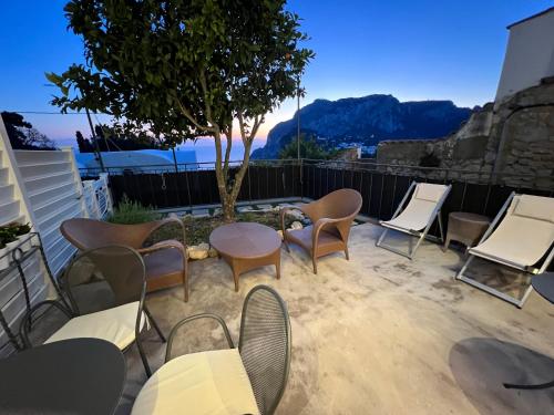 a patio with chairs and tables and a tree at La Reginella Capri in Capri