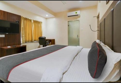a bedroom with a large white bed and a desk at Hotel KGB Coolriver in Visakhapatnam
