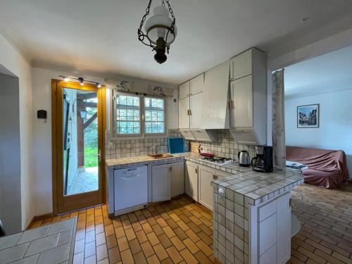 une cuisine avec des placards blancs et une porte donnant sur une cour. dans l'établissement Grande maison landaise près du port de Capbreton, 4 chambres, jardin, animaux admis - FR-1-413-232, à Capbreton