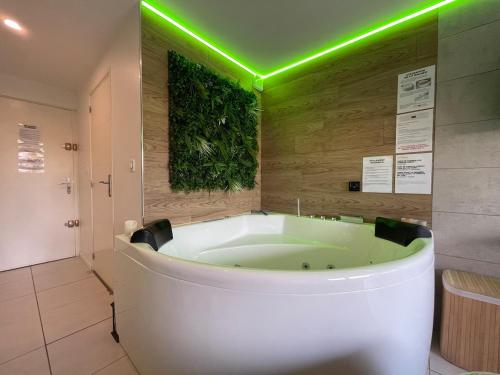 La salle de bains est pourvue d'une baignoire et de lumières vertes. dans l'établissement Studio Cosy SPA Balneo et terrasse, au Cap d'Agde