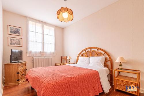 Cette chambre comprend un lit avec une couverture rouge et une télévision. dans l'établissement Grand T2 en 1ère ligne Vue mer sur le Petit Port, à Arcachon