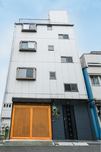 a tall white building with an orange door at Six7 APT三ノ輪 in Tokyo