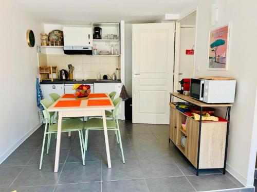 une cuisine avec une table et des chaises dans une cuisine dans l'établissement Apt T3 avec terrasse, sous les pins, au bord du lac et à 5 min de l'océan, à Carcans
