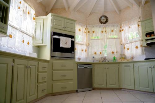 a kitchen with green cabinets and a clock on the wall at Marzalea 5 Bd Villa by ZenBreak in Saint James