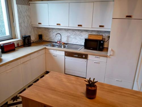 - une cuisine avec des placards blancs, un évier et une table dans l'établissement Chez Jimmy London, à Mulhouse