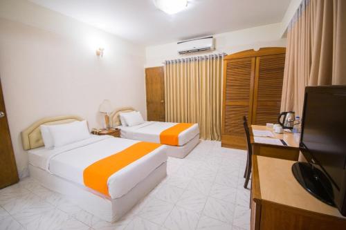 ein Hotelzimmer mit zwei Betten und einem Flachbildfernseher in der Unterkunft Elegant Enchanted in Dhaka