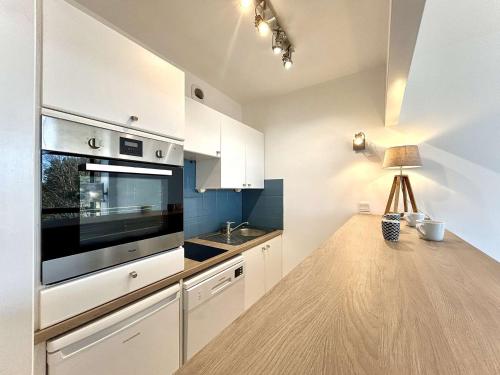 une cuisine avec des armoires blanches et un comptoir en bois dans l'établissement Appartement calme avec terrasse à 2 pas de la plage Benoît, 2 pièces, 4 couchages, La Baule - FR-1-245-103, à La Baule