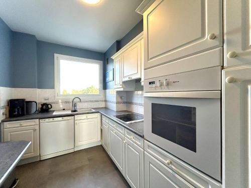 une cuisine avec des armoires blanches et une fenêtre dans l'établissement Appartement T3 Face Mer à La Baule avec Terrasse et Parking Privé, 4 Couchages - FR-1-245-97, à La Baule