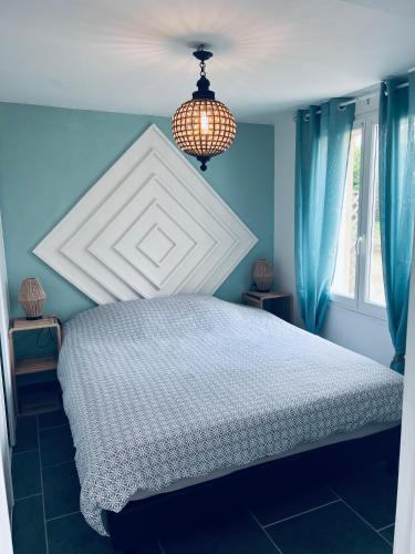 - une chambre bleue avec un lit et un lustre dans l'établissement Le Petit Breuil, à Sarlat-la-Canéda