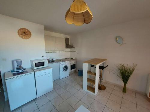 une cuisine avec un réfrigérateur et un micro-ondes dans l'établissement Lumineux 2 pièces à 50m de la plage avec ascenseur, loggia et équipements pour 4 personnes - FR-1-423-242, au Grau-dʼAgde
