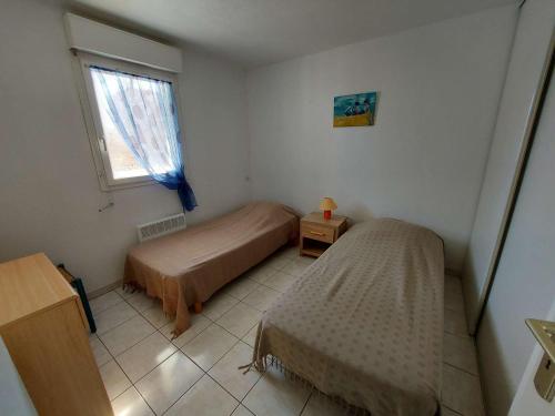une petite chambre avec deux lits et une fenêtre dans l'établissement Lumineux 2 pièces à 50m de la plage avec ascenseur, loggia et équipements pour 4 personnes - FR-1-423-242, au Grau-dʼAgde
