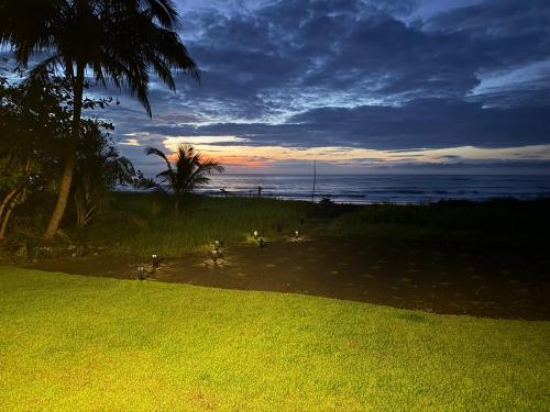 a sunset on the beach with a palm tree and the ocean at Casa Marea in Cambutal